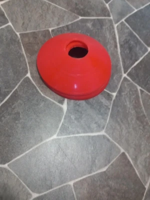 Röda markeringskoner i plast - Säljer ett gäng röda markeringskoner i plast, perfekta för träning, sport eller lekar. Konerna är runda med ett hål i mitten och stapelbara för enkel förvaring. Smidiga att använda på både gräs och inomhusgolv.