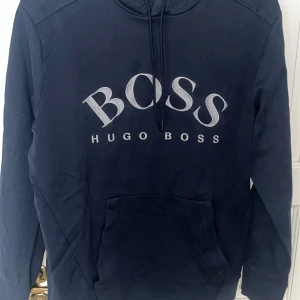 Mörkblå hoodie från Hugo Boss - Snygg mörkblå hoodie från Hugo Boss med stor logga på bröstet. Storlek L men sitter mer som en M.