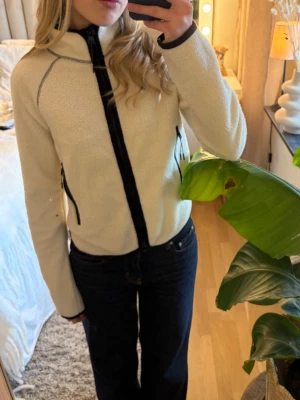 Vit fleecejacka med svarta detaljer - Säljer en vit fleecejacka med svarta dragkedjor och detaljer. 💕