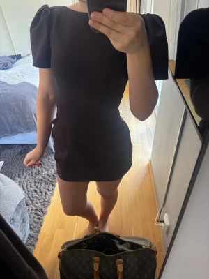 Brun kort puffärmad klänning - Snygg brun kort klänning med puffärmar och rund halsringning. Klänningen har en figurnära passform och är perfekt för dig som gillar en stilren look. 