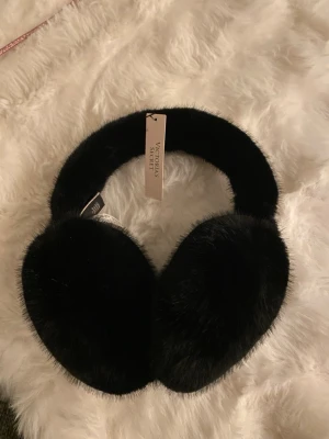 Öronmuffar Victoria's Secret - Snygga och fluffiga svarta öronmuffar från Victoria's Secret med mjuk fuskpäls och VS-logga i metall på sidan. Perfekta för att hålla värmen och samtidigt se stilren ut. Klassisk rund form. Aldrig använda💓💕💕💕💕💓