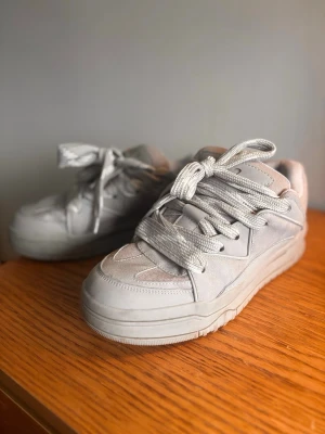 Grå chunky sneakers - Snygga chunky sneakers i ljusgrått med breda, matchande skosnören. Ovandelen är i en mix av mocka och slätt läder för en cool kontrast. Tjock sula ger extra attityd och streetkänsla. Perfekta för dig som gillar en clean och modern stil. Helt nya och använda 1 gång. Skriv för fler bilder eller om du har en fråga! 😄