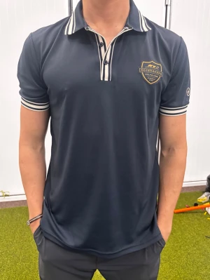 Mörkblå piké från Österåkers Golfklubb - Snygg mörkblå pikétröja från Österåkers Golfklubb med klubbens logga på bröstet. Ny pris 900kr. 