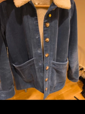 Blå manchesterjacka - - Oversized stil - Avtagbart innerfoder - Längd från axeln: 72 cm (storlek XS)  Passar normal storlek XS–M. Endast kemtvätt.