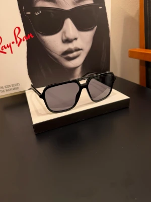 Svarta solglasögon från Dolce & Gabbana - Snygga svarta solglasögon från Dolce & Gabbana med rektangulära bågar och mörka glas. Klassisk och stilren design med logotyp på skalmen. Perfekta för att lyfta din look med en modern touch.