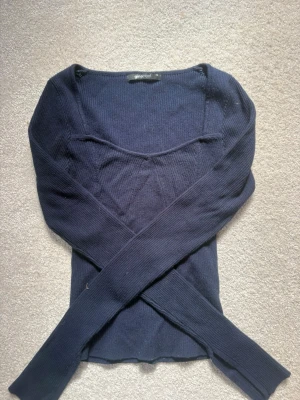 Mörkblå ribbad  topp Gina Tricot - Snygg mörkblå ribbad topp från Gina Tricot i storlek XS. Tröjan har lång ärm, ribbstickad struktur och en feminin, något djupare urringning.   KNAPT ANVÄND! Pris kan diskuteras vid snabb affär 💓🫶 