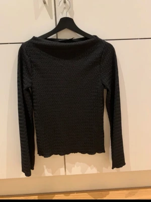 Svart långärmad topp  - Säljer en svart långärmad topp. Har en fin rag slits vid kragen. Aldrig använd. Prislapp sitter kvar.