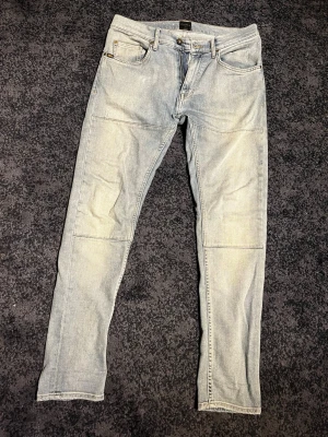 Ljusblå jeans från tiger of sweden  - Säljer ett par ljusblå jeans med raka ben och coola paneldetaljer över låren. Klassisk femficksmodell och normal midja. Jeansen har en avslappnad vibe och är tillverkade i denim med en snygg tvätt. 30/34