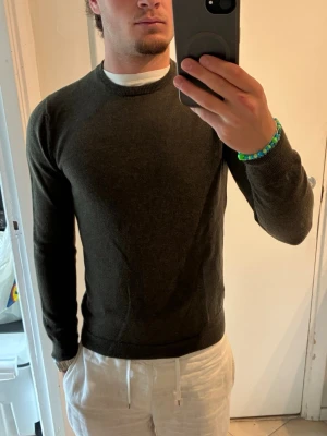 Mörkgrön stickad tröja Weekday - Säljer en mörkgrön stickad tröja från Weekday med rund halsringning och långa ärmar. Tröjan har en enkel och stilren design med ribbade muddar vid ärmslut och nederkant. Perfekt för lager på lager och passar till det mesta. Mycket fint skick, Storlek S men sitter som xs/xxs
