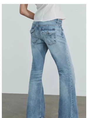 Ljusblå bootcut jeans med fickdetaljer - Snygga ljusblå bootcut jeans med fickor bak som har lock och knappdetaljer. Jeansen har en klassisk femficksdesign och är tillverkade i denim med lätt tvättad look. Perfekta för en avslappnad och trendig stil.