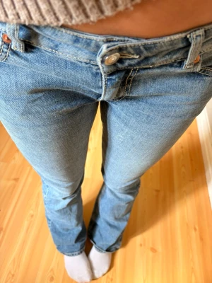 Ljusblå bootcut jeans  - Säljer ett par ljusblå bootcut jeans. Jeansen har klassisk femficksmodell, normalhög midja och utsvängda ben. Tillverkade i mjuk denim med snygg tvätt och silverfärgade knappar. Perfekta för en trendig och avslappnad look.