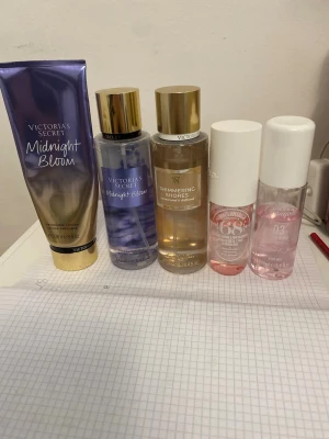 Parfymset från Victoria's Secret sol de janerio - Säljer ett parfymset med tre Victoria's Secret body mists: Midnight Bloom i lila och guld, Shimmering Shores i guld och transparent samt två mindre rosa och vita parfymer från andra märken. Flaskorna är i plast med gulddetaljer och sprayfunktion. Skriv för frågor 
