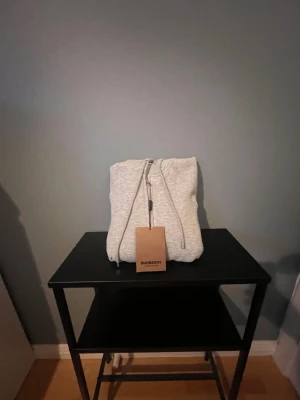 Grå zip hoodie från Burberry - Snygg grå zip hoodie från Burberry med klassiskt rutigt foder i huvan och justerbara snören. Tillverkad i mjukt bomullsmaterial och har ribbade muddar vid ärmslut och nederkant. Perfekt för en chill och stilren look. Storleken är M men jag skulle säga att en S eller XS skulle passa för den är ganska liten i storlek priset går att diskutera 