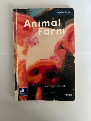 Animal Farm av George Orwell - Animal Farm av George Orwell i Longman Fiction-serien. Omslaget har en färgstark illustration av en gris i rosa, rött och vitt. Boken är i pocketformat och har blå baksida med text och information om innehållet. Perfekt för dig som gillar klassisk samhällskritik.