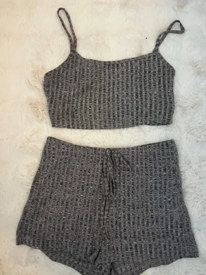 Grått ribbat set med shorts och topp - Mysigt tvådelat set i grått ribbat tyg med croppad topp med smala axelband och matchande shorts med knyt i midjan. Perfekt för chill hemma eller som underkläder. Mjukt material och avslappnad passform. Från shein 