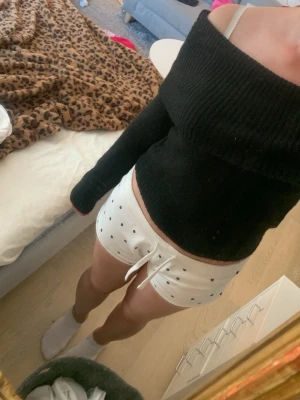 Svart off shoulder stickad tröja - Trendig svart stickad tröja med off shoulder-design och bred ribbad kant upptill. Långa ärmar och mjukt material som sitter snyggt på kroppen. Perfekt för dig som vill ha en stilren och modern look.