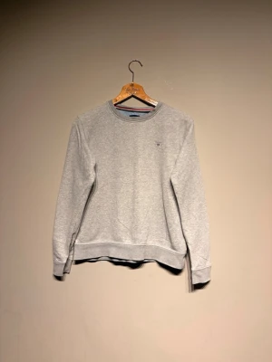 Grå sweatshirt från GANT - Klassisk grå sweatshirt från GANT med rund halsringning och broderad logga på bröstet. Tröjan har ribbade muddar vid ärmslut och nederkant. Perfekt basplagg i mjukt material som funkar året runt.
