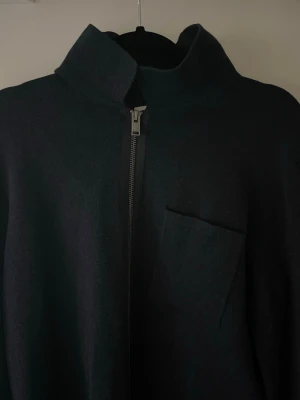 Mörkblå tröja med dragkedja från Selected Homme - Stilren Mörkblå kofta från Selected med hög krage och dragkedja framtill. Koftan har en enkel bröstficka och är tillverkad i ett mjukt material som passar perfekt till lager på lager. Långärmad och minimalistisk design.