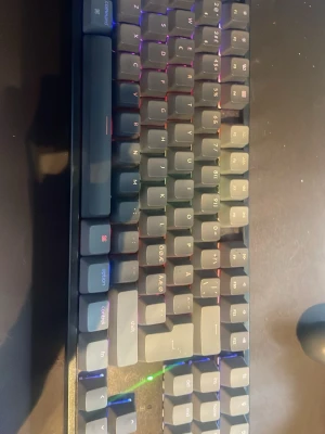Keychron K8 trådlöst mekaniskt tangentbord - Säljer ett Keychron K8 trådlöst mekaniskt tangentbord med RGB-belysning. Tangentbordet har en kompakt design med svarta och gråa tangenter och är tillverkat i plast. Perfekt för gaming eller arbete vid datorn.