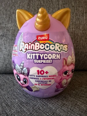 NY! Rainbocorns Kittycorn Surprise ägg - Ny oöppnad!  Rainbocorns Kittycorn Surprise är ett överraskningsägg med kattema. Varje ägg innehåller en plyschkatt, klistermärken, en samlarguide och andra överraskningar. Det finns 8 olika Kittycorns att samla på.