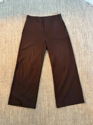 Bruna vida byxor från Lindex - Säljer ett par bruna byxor från Lindex, modell Lykke. Byxorna har vida ben och hög midja samt sidofickor. Perfekta för en avslappnad och trendig stil. Materialet känns mjukt och följsamt.