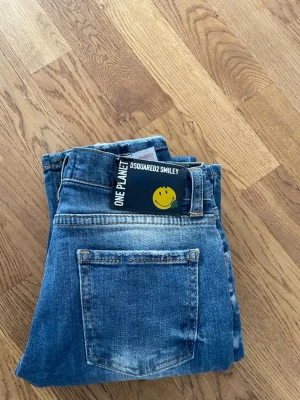 Blå slitna jeans från Dsquared2 - Säljer ett par blå jeans från Dsquared2 med slitningar och distressed detaljer. Jeansen har klassisk femficksmodell, normal midja och raka ben. Materialet är denim i bomull och de har en cool, avslappnad vibe. Tror ja aldrig använt dessa jeans och de är för små bara legat i garderoben inte kommit till användning. Står 12år som storlek skulle gissa på att de är 164 i storlek 