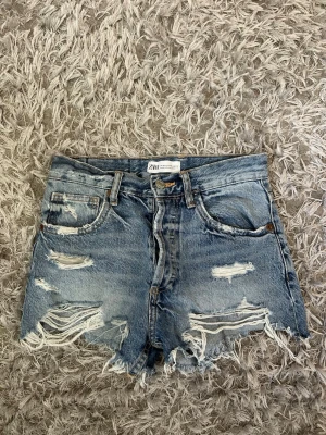 Zara jeans shorts  - Ett par blåa jeansshorts från Zara. Shortsen har flera slitningar framtill och även på bakfickorna. Fint skick, storlek 32💗