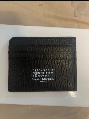 Maison Margiela korthållare - Snygg maison Margiela korthållare. Köpt på Plick men föll mig ej i smaken och användes ej. Köparen var osäker på äktheten men känns bra men har ej bevis på att den är äkta tyvärr. Men bra kvalitet och fin box., vid frågor kom DM. 😀