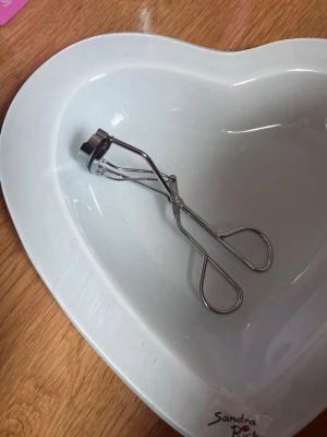 Silverfärgad ögonfransböjare - En klassisk ögonfransböjare i silverfärgad metall med ergonomiskt handtag. Perfekt för att skapa snygg böj på fransarna. Enkel och smidig design som passar i sminkväskan.