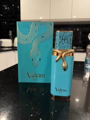 Vulcan Feu  - Unik parfymflaska i turkos med guldfärgade detaljer och en orm som slingrar sig runt korken. Förpackningen matchar flaskan med samma turkosa färg och orm-motiv. Flaskan har en lyxig och modern design som sticker ut i badrumshyllan.