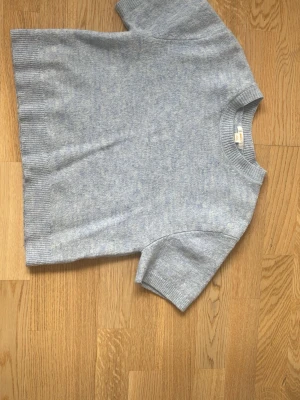 Ljusblå stickad t-shirt - Säljer en ljusgrå stickad t-shirt med korta ärmar från Gina tricot. Tröjan har använts ett par gånger men har inga  defekter eller hål. 