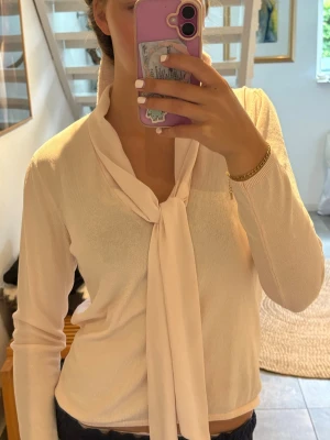 Ljusrosa blus  - Snygg ljusrosa blus med långa ärmar och ett elegant knytband vid halsen. Blusen har en mjuk och tunn känsla, perfekt för en stilren look. Passar till både jeans och kjol för en trendig outfit.