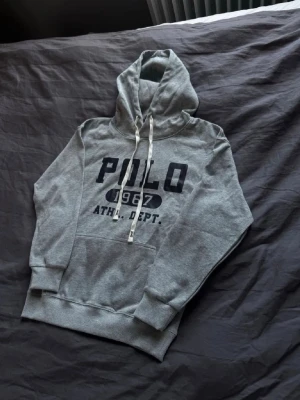 Grå hoodie med POLO-tryck - Snygg grå hoodie från Polo. Säljer då den är lite liten på mig. Skick 10/10. Storlek M. Kan sänka priset vid snabb affär. Skriv vid funderingar!