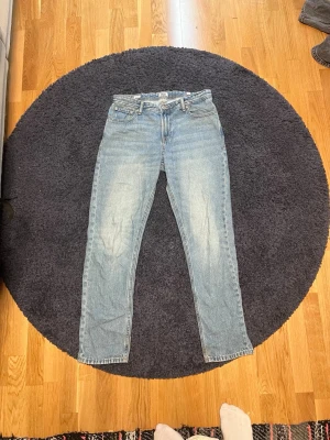 Ljusblå raka jeans från Jack & Jones - Säljer ett par ljusblå jeans från Jack & Jones med klassisk femficksdesign och raka ben. Jeansen har en snygg tvättad look och är tillverkade i slitstark denim. Perfekta för en avslappnad och trendig stil.