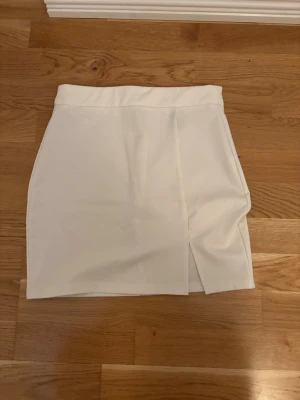 Vit kortkjol med slits - Stilren vit kortkjol med slits framtill. Avklippt lapp så vet tyvärr ej märket då den är gammal. Passar storlek xs och s💕