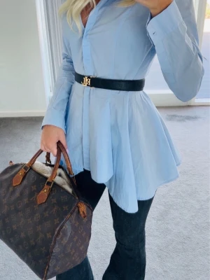 Ljusblå blus - Snygg ljusblå skjorta. Skjortan har lång ärm, klassisk krage och ett flowy, utsvängt avslut. Perfekt för dig som vill ha en trendig look
