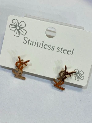 Guldiga  örhängen - Snygga örhängen i rostfritt stål med guldig färg. Små och stilrena studs som passar perfekt till dig som gillar minimalistisk design och vill ha en touch av lyx i din look. Lätta att bära och enkla att matcha med andra accessoarer.