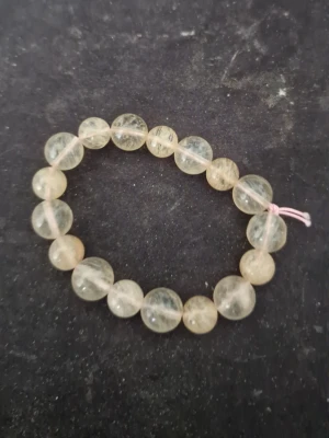 Elastiskt armband med ljusa pärlor - Snyggt armband med runda, ljusgula pärlor av genomskinlig sten. Trädd på elastisk tråd med en enkel knut. Perfekt för dig som gillar stilrena accessoarer med naturlig känsla.