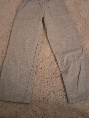 Gråa mjukisbyxor med raka ben - Säljer ett par gråa mjukisbyxor med raka ben och resår i midjan. Byxorna har två fickor fram och två bakfickor. Perfekta för chill dagar hemma eller när du vill ha det extra bekvämt. Materialet känns mjukt och stretchigt.