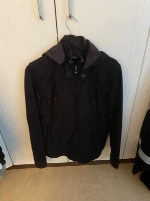 Svart cardigan från Hugo boss med luva  - Snygg svart cardigan från Hugo boss som passar till det mesta. Jag använde den i skolan och på stan. Den är perfekt under våren/hösten då det inte är så kalt. Hör gärna av er och kom med bud 
