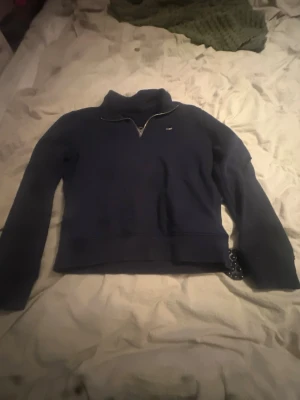 Mörkblå halvzip sweatshirt från lexinton - Mörkblå sweatshirt från Gant med halv dragkedja och liten broderad logga på bröstet. Tröjan har hög krage och långa ärmar, perfekt för en avslappnad och stilren look. Passar till jeans eller mjukisbyxor.