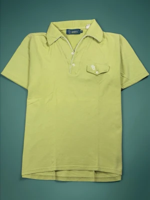 Ljusgrön rare vintage pikétröja från J.Lindeberg  - Snygg ljusgrön pikétröja från J.Lindeberg med klassisk krage, korta ärmar och knappslå framtill. Tröjan har en liten bröstficka med broderad logga och vita detaljer längs kragen. Perfekt för en avslappnad men stilren look.