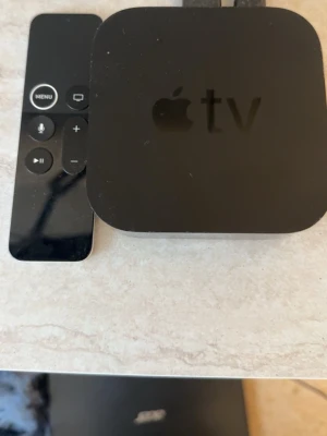Apple TV 32GB med fjärrkontroll - Apple TV modell A1625 med 32GB lagring. Kommer med svart fjärrkontroll och har en stilren, fyrkantig design i svart plast. Perfekt för streaming och appar direkt till din TV
