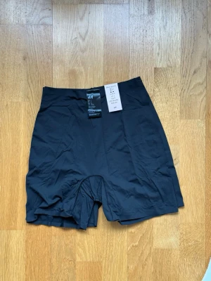 Svarta biker shorts från H&M - Säljer ett par svarta biker shorts från H&M med hög midja. De är tillverkade i ett stretchigt material av polyester och elastan, perfekta för en sportig och bekväm look. Passar till träning eller när du vill ha en chill outfit.