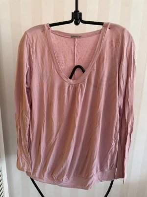 Benetton Ljusrosa långärmad topp - Säljer en enkel och mjuk ljusrosa långärmad topp med rundad v-ringning. Toppen har en avslappnad passform och är tillverkad i ett tunt, skönt material som passar perfekt till jeans eller kjol.