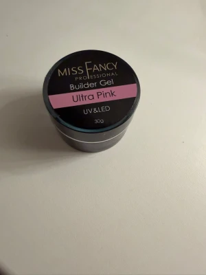 Miss Fancy Builder Gel Ultra Pink - Builder Gel Ultra Pink från Miss Fancy, 30g. Gelen har en snygg ljusrosa färg och passar perfekt för att bygga och forma naglar. Kan användas med både UV- och LED-lampa. Kommer i en rund burk med skruvlock. den är helt oanvänd och nästan helt full jag har bara använt den en gång.