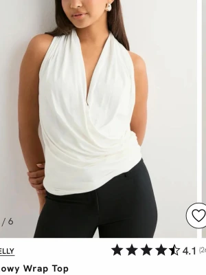 Vit omlottopp med djup v-ringning - Säljer en helt ny snygg vit omlottopp från Nelly med prislappen kvar 