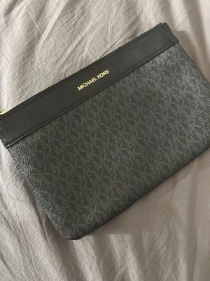 Svart kuvertväska Michael Kors - Svart Michael Kors Clutch, skick 8/10 små defekter finns men är inte så synliga. Pris kan diskuteras vid snabb affär 