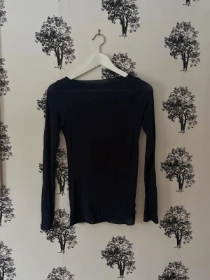 Mörkblå långärmad intimissi topp - En enkel och stilren mörkblå långärmad topp med rund halsringning. Toppen har en tight passform och är tillverkad i ett mjukt, stretchigt material som känns bekvämt mot huden. Perfekt att matcha med jeans eller kjol för en clean look. Finns en reva där fram! Inget som syns när den är på riktigt!💓🌸