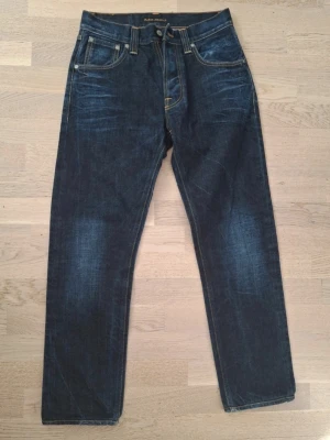 Mörkblå jeans från Nudie Jeans - Snygga mörkblå jeans från Nudie Jeans med klassisk femficksmodell och kontrastsömmar. Jeansen har en rak passform och är I modellen big bengt. Storlek 29/32. Meddela gärna om du är intresserad 